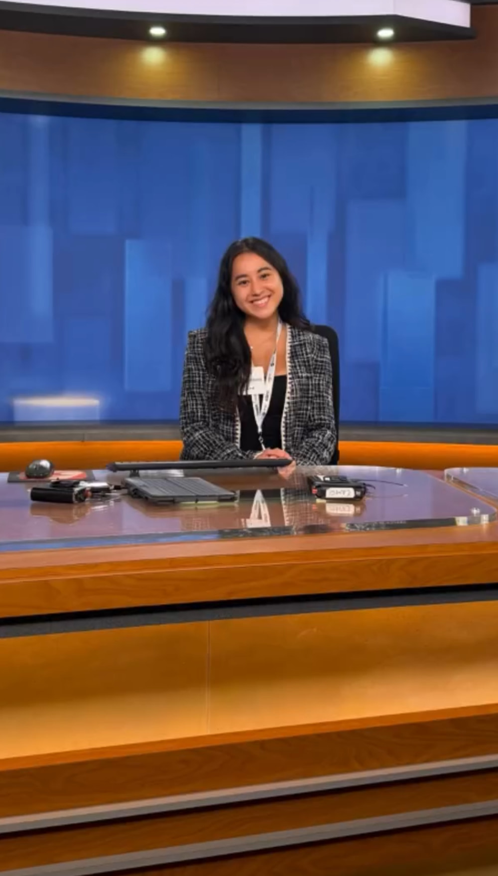 Leah Gavilan seated at a television news anchor desk during JCamp.
