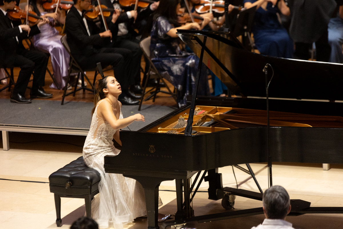 Leah Gavilan at the piano with full orchestra behind her.