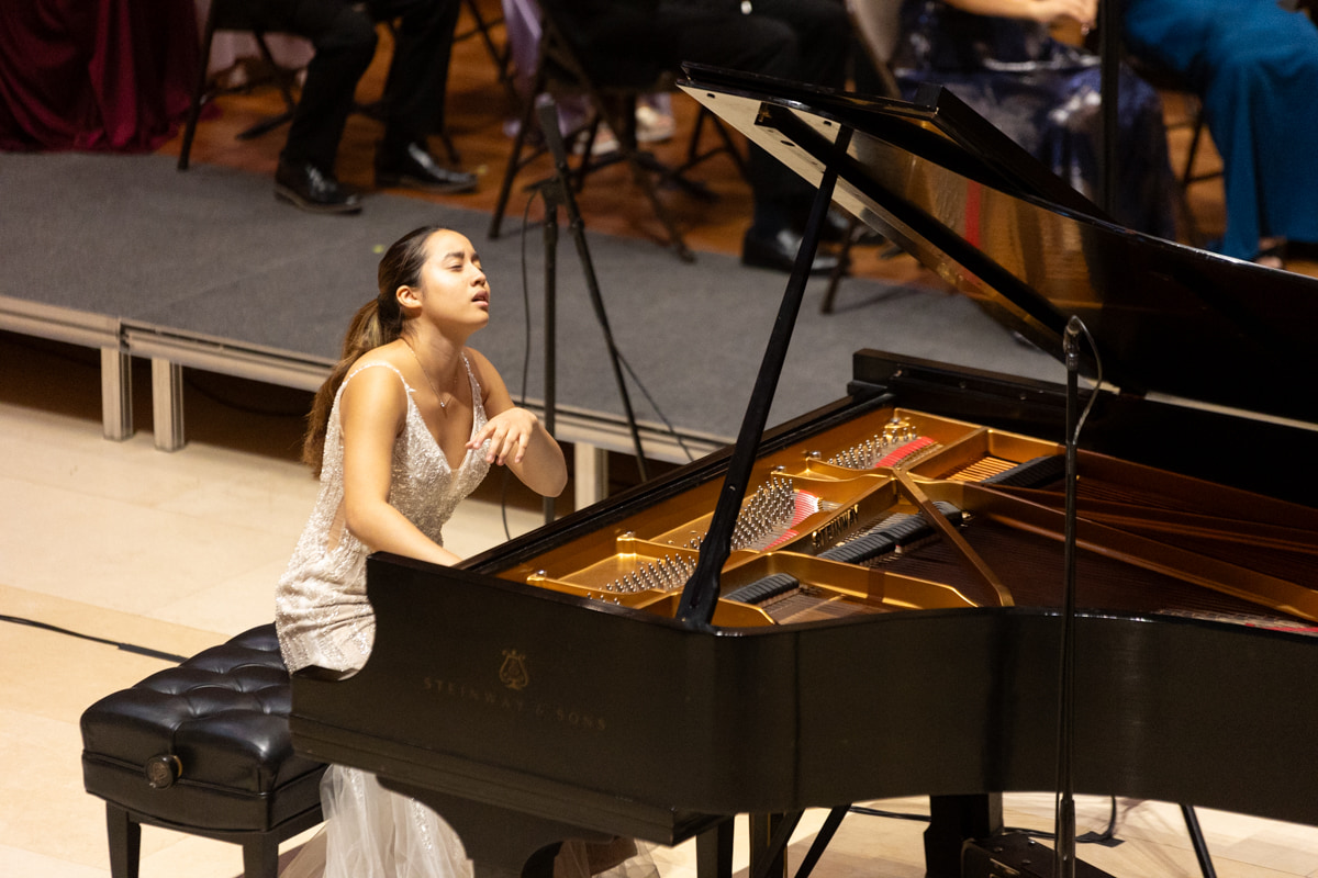 Leah Gavilan playing the piano with orchestra.